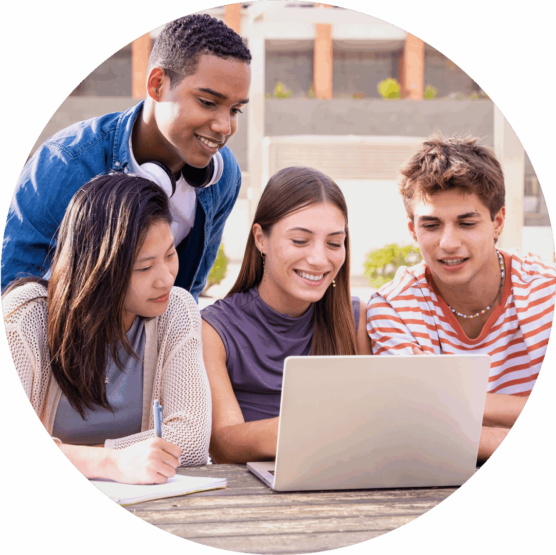 Students collaborating around a laptop outdoors.