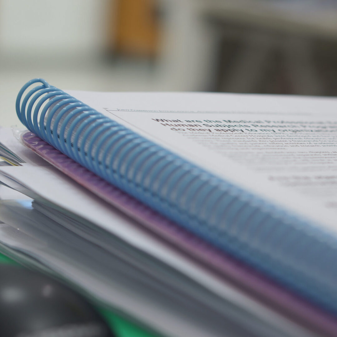 Stack of spiral-bound documents on desk.